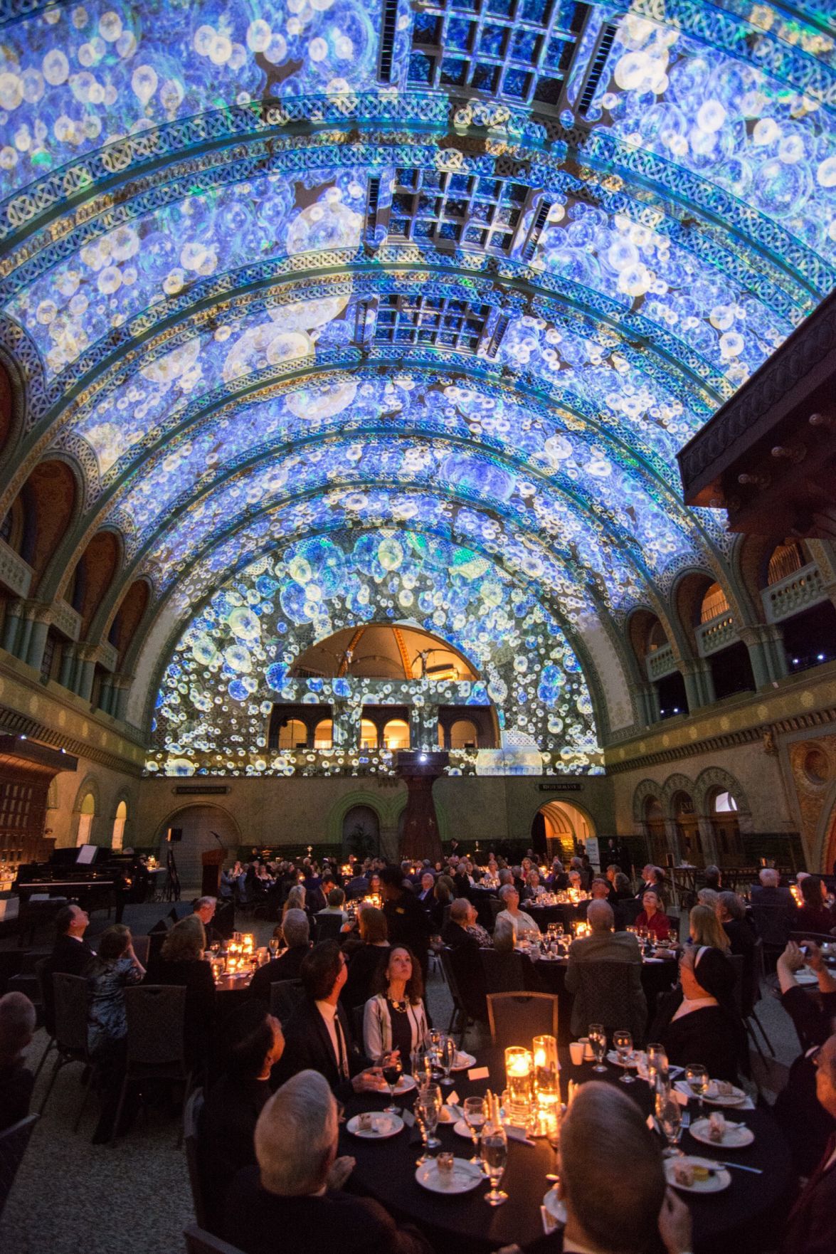 Guests have dinner and watch the light show on the ceiling of the Grand Hall in Union Station